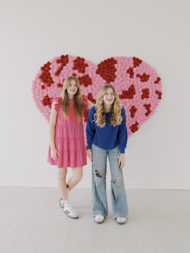 twin girls laugh while in front of giant heart in colorado springs studio