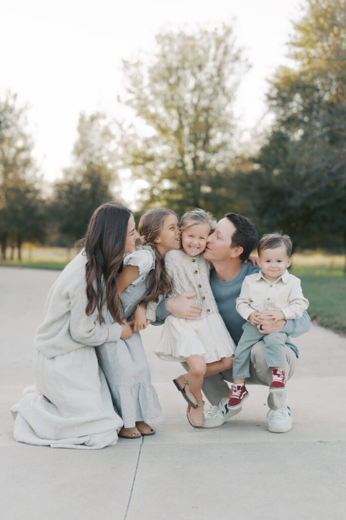 family of five huddled together kissing youngest daughter for Colorado Springs family photographers