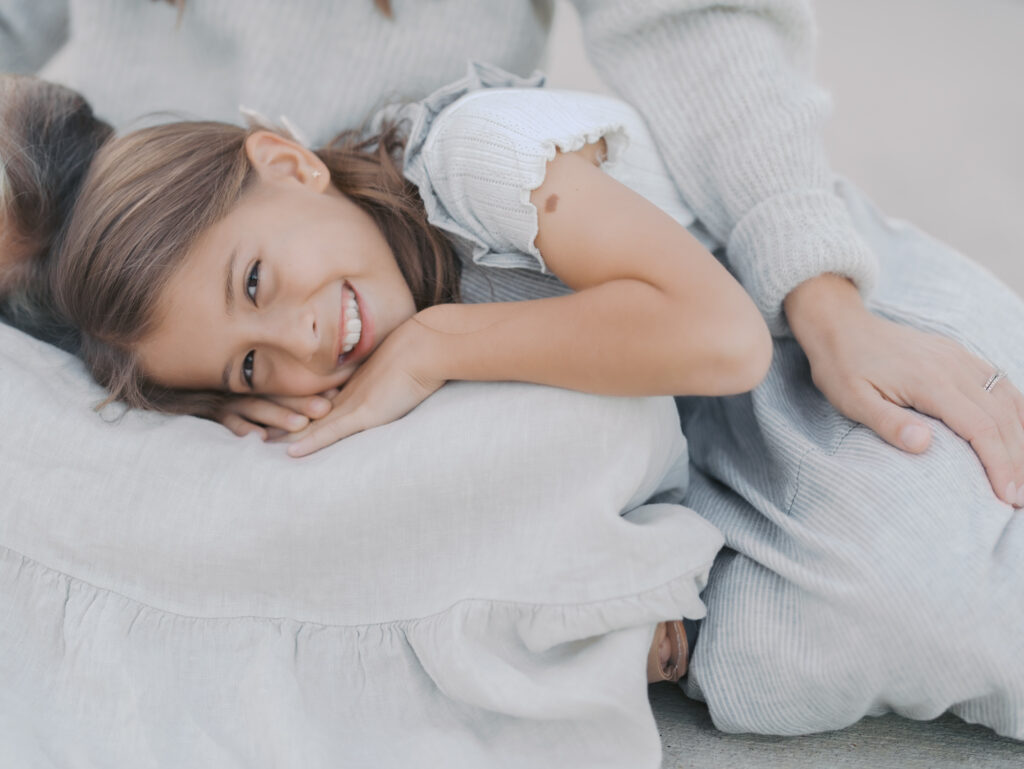 girl smiling with head in moms lap for Colorado Springs family photographers