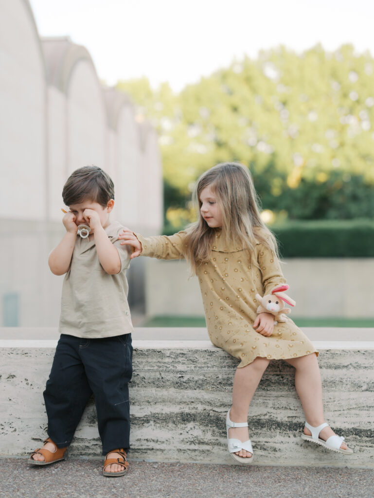 little girl helping brother as he is crying 