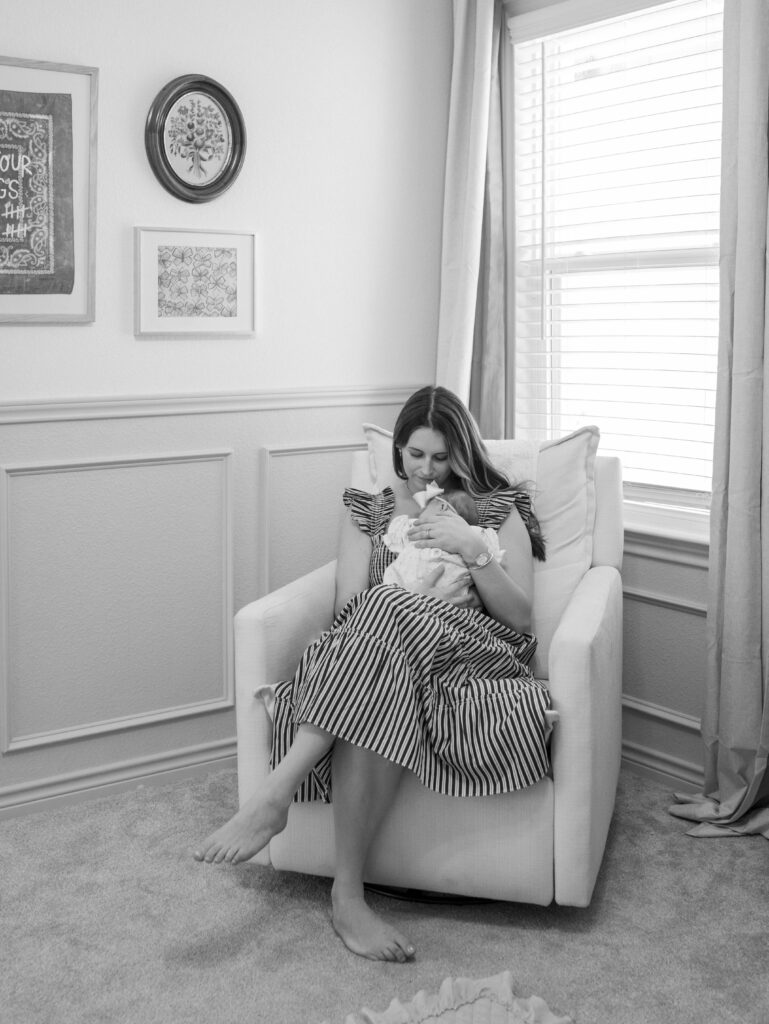 mom sitting in chair in nursery with newborn baby in arms Newborn Photos Colorado Springs