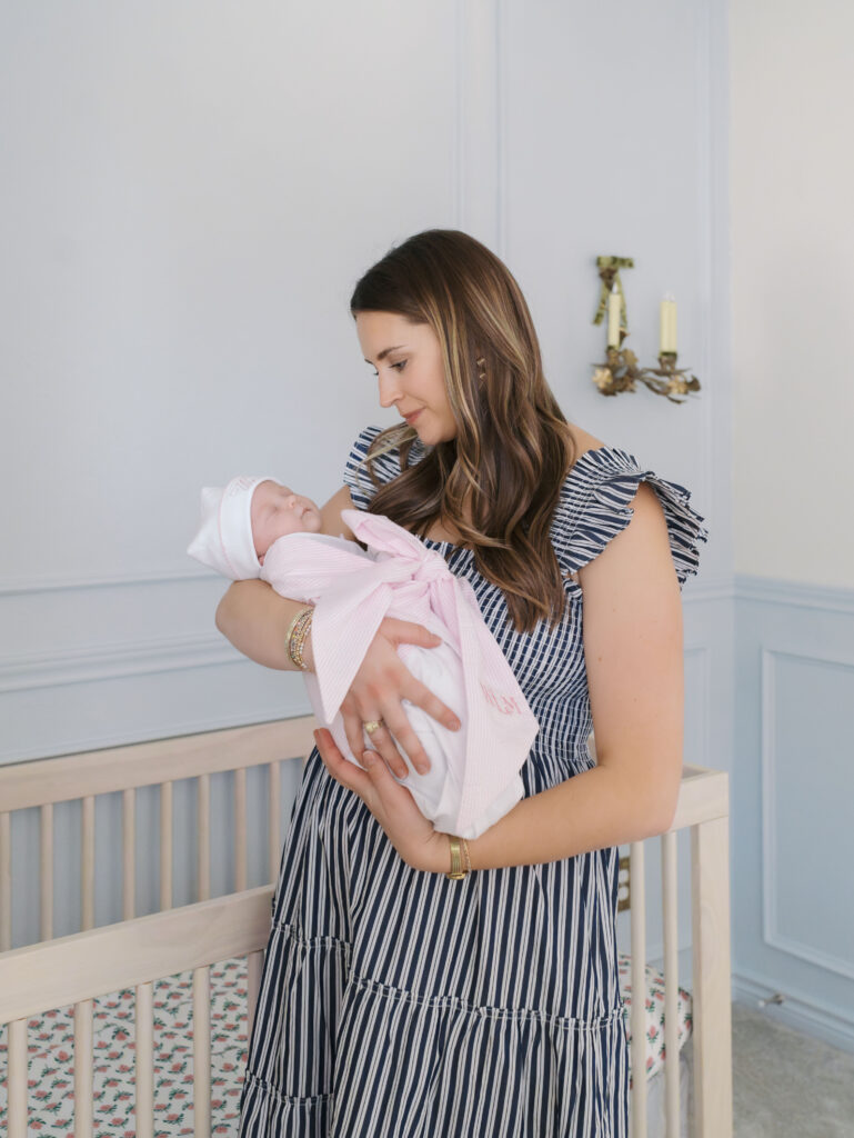 mom holding newborn baby in arms looking down at her