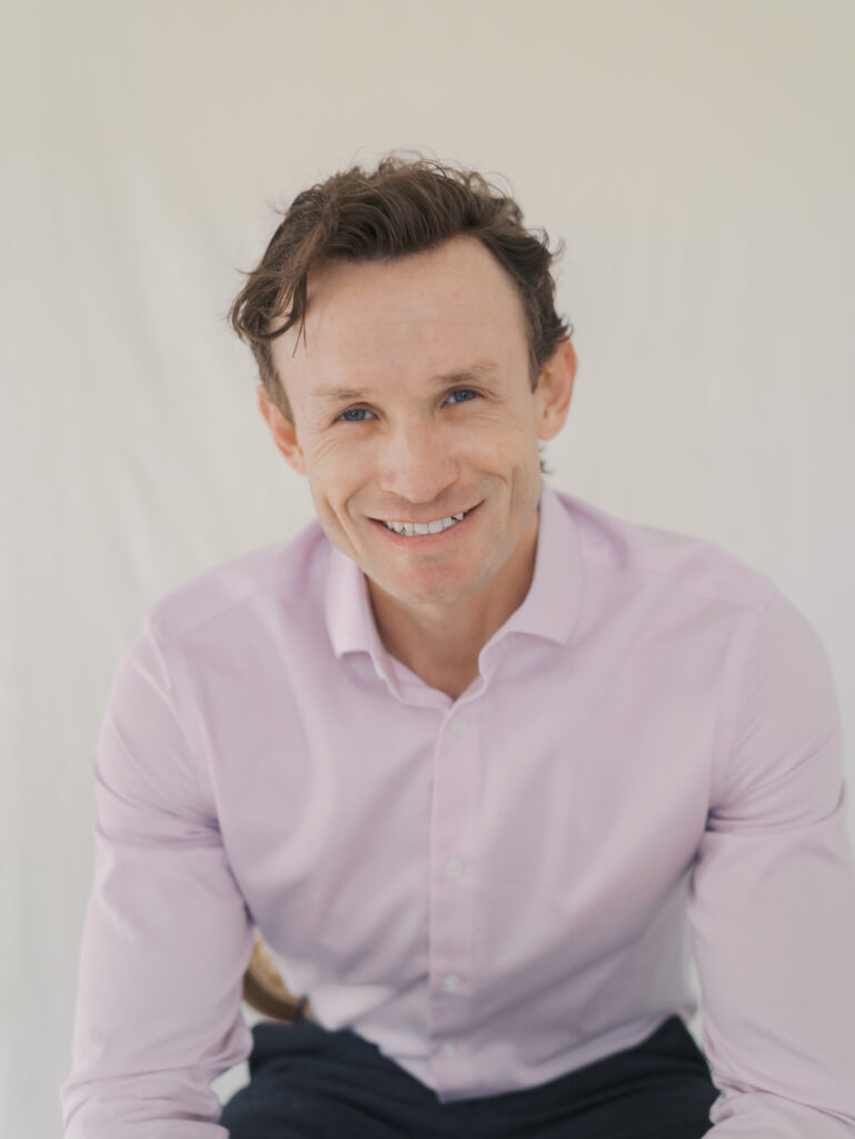man smiling at camera sitting in a chair for headshots in colorado springs