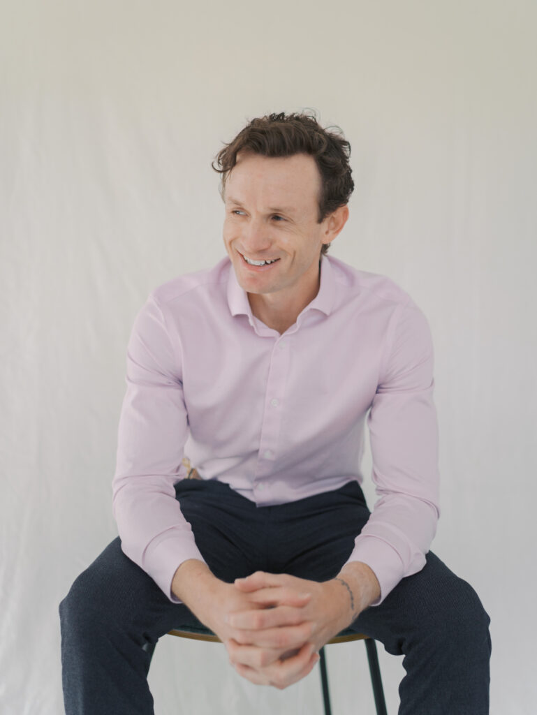 small business owner sitting in chair while looking off to the side smiling during his headshots in colorado springs