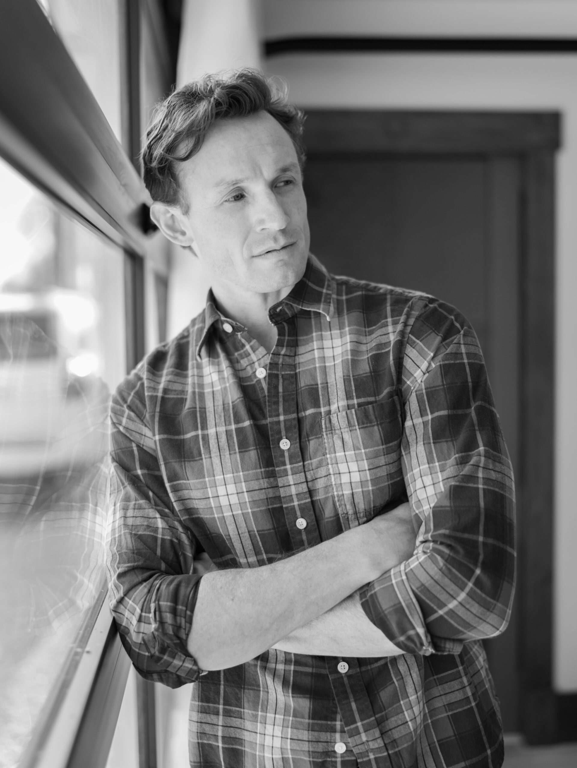 small business owner in studio leaning against window wall for headshots in colorado springs