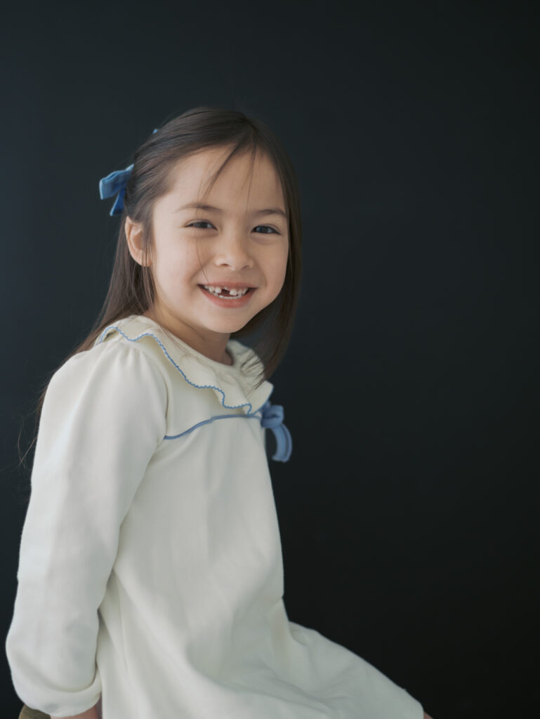 girl smiling at camera with black background
