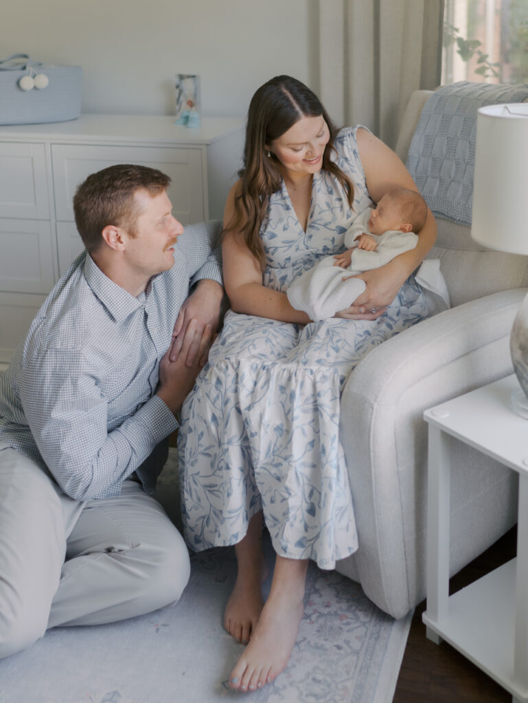 parents sitting on chair lovingly looking at newborn baby