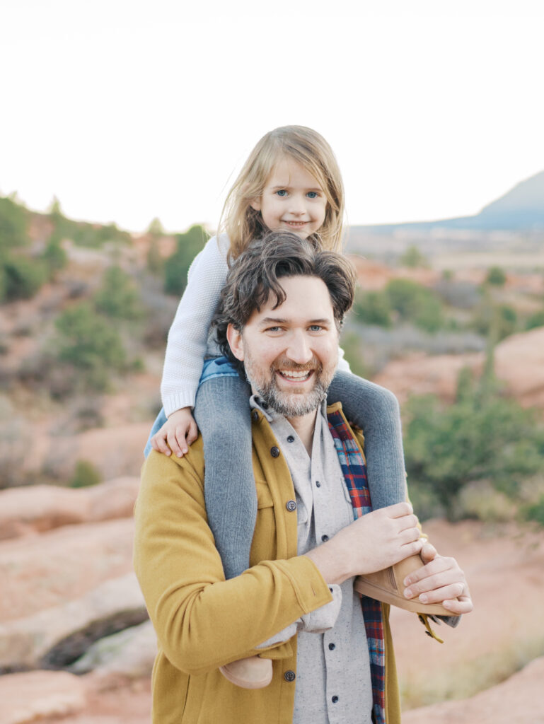 girl on dad's shoulders smiling