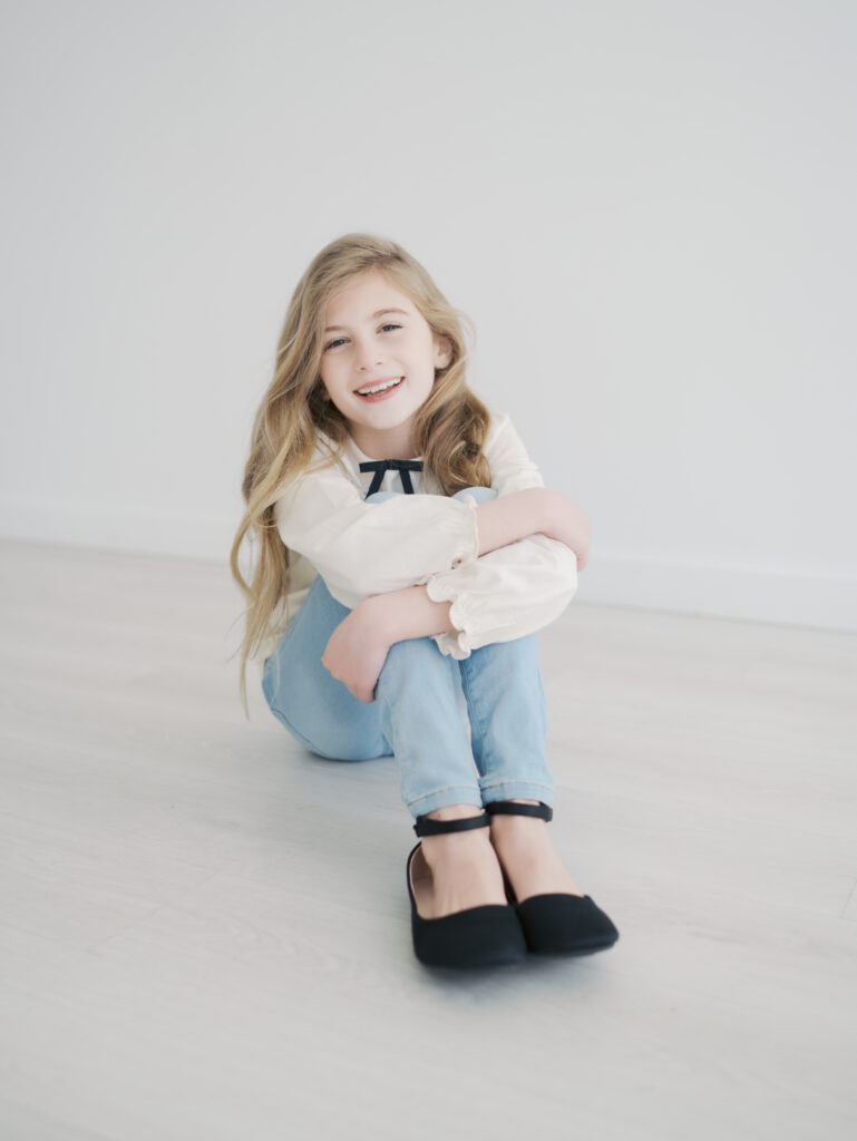 preteen girl sitting with legs stretched out front and arms draped over knees for Kid Mini Colorado Springs
