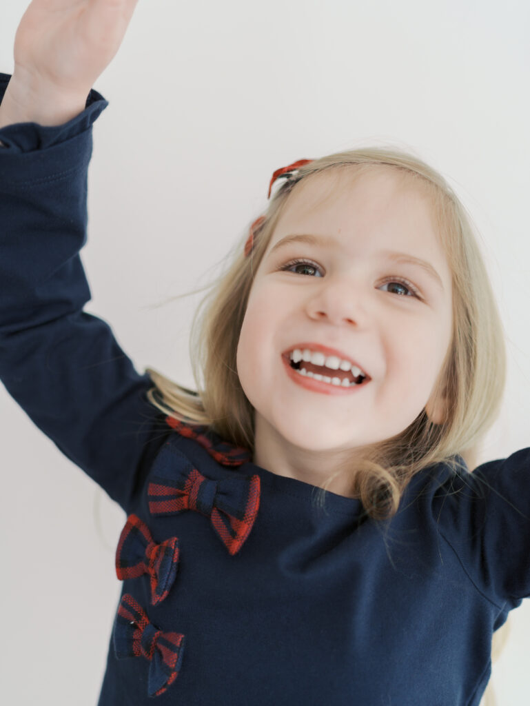 close up girl smiling big with arms overhead for Kid Mini Colorado Springs
