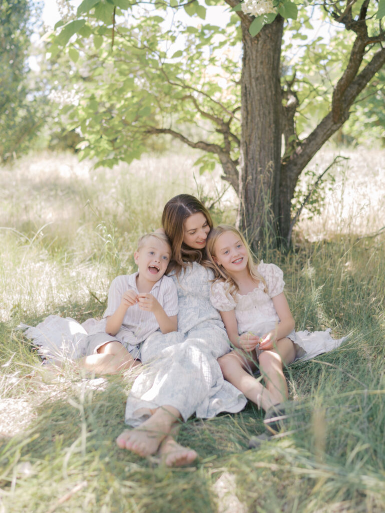 mom sitting with kids on blanket in graa laughing and smiling for Photographer Colorado Springs CO