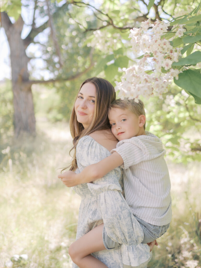 mom with son on back in beautiful are with blooming flowers