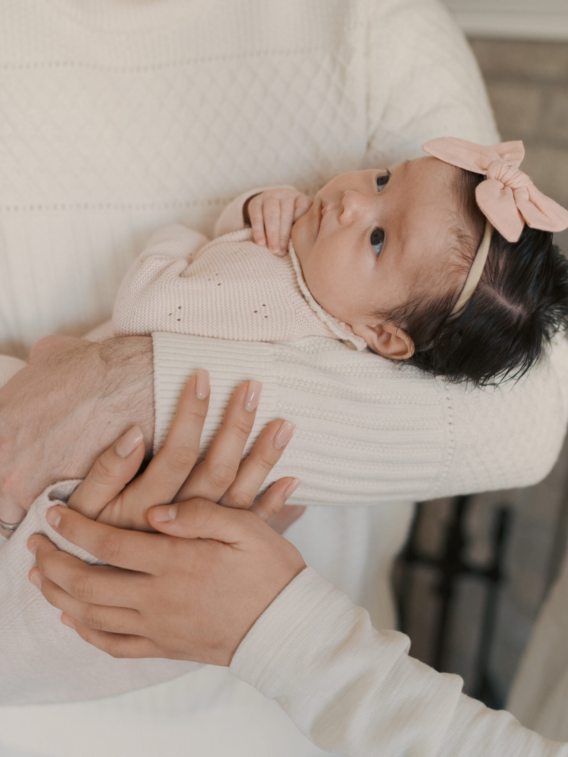 newborn girl in dad arms with big brothers hands wrapped around too for when to schedule newborn photos in colorado springs