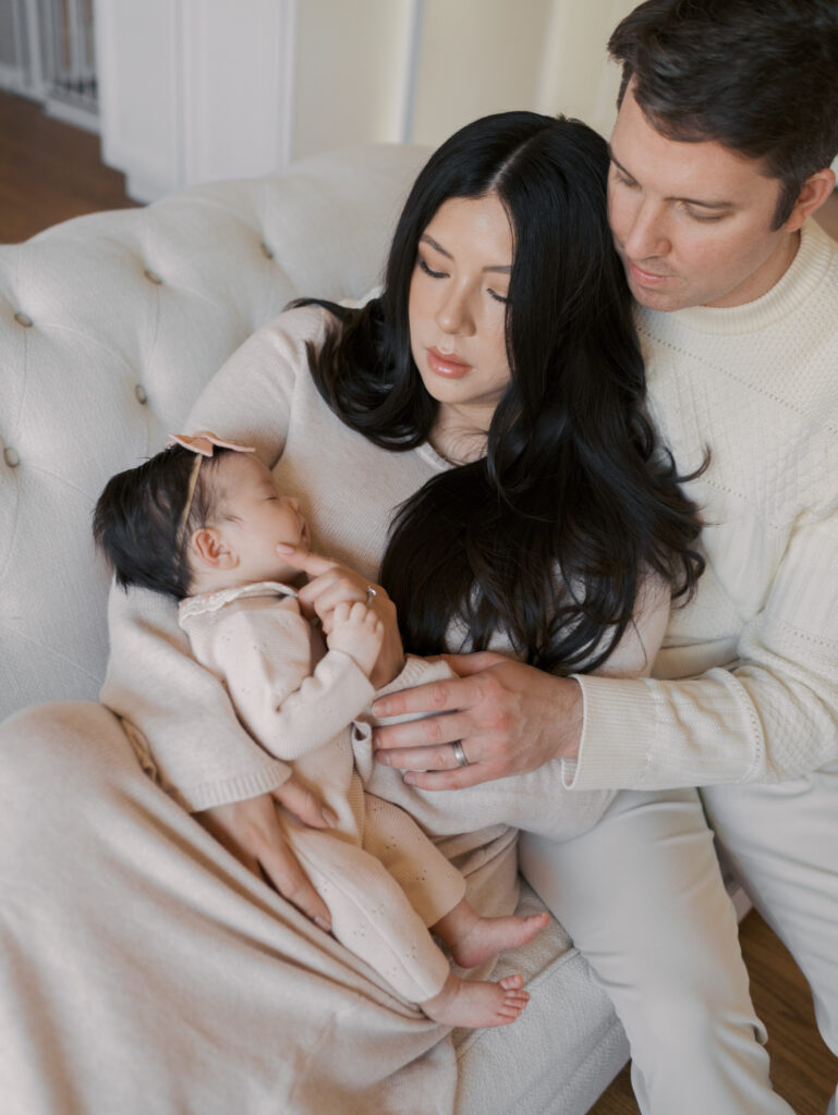 mom dad snuggled on couch with newborn baby for newborn photo session in colorado springs