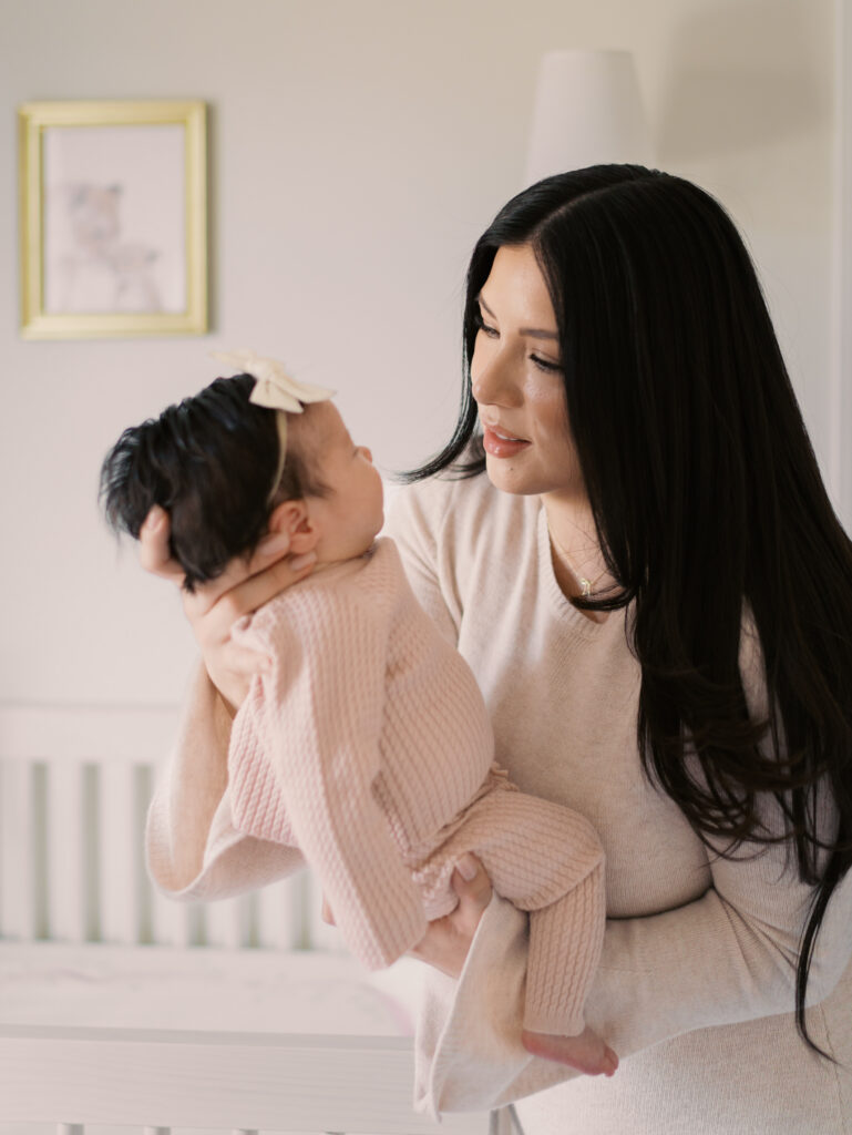 mom holding and looking down at newborn baby in nursery