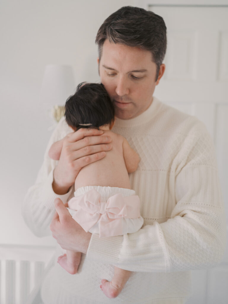 dad holding newborn showing initials in bloomers