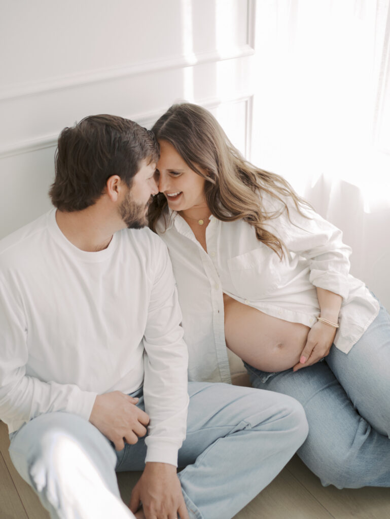 couple sitting by window for maternity photos in colorado springs