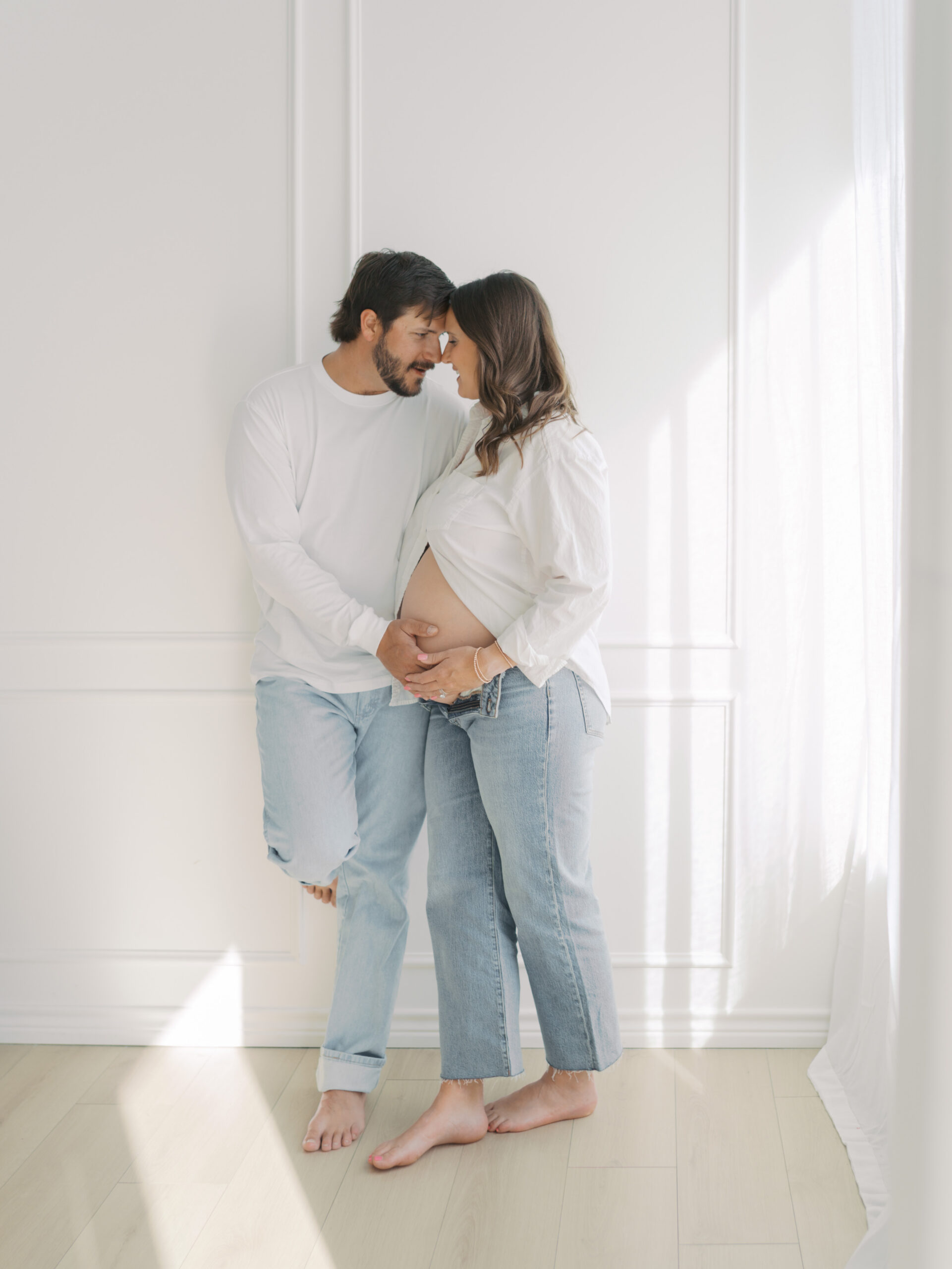 couple nuzzled together standing during a studio maternity session in colorado springs