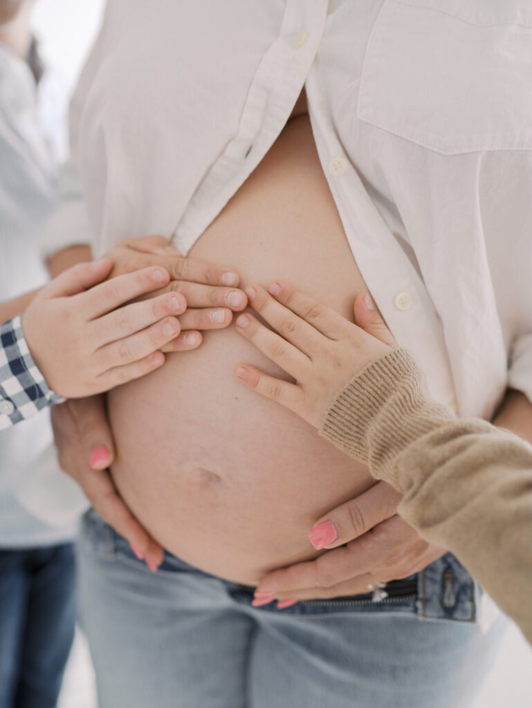 siblings hands on expecting moms belly