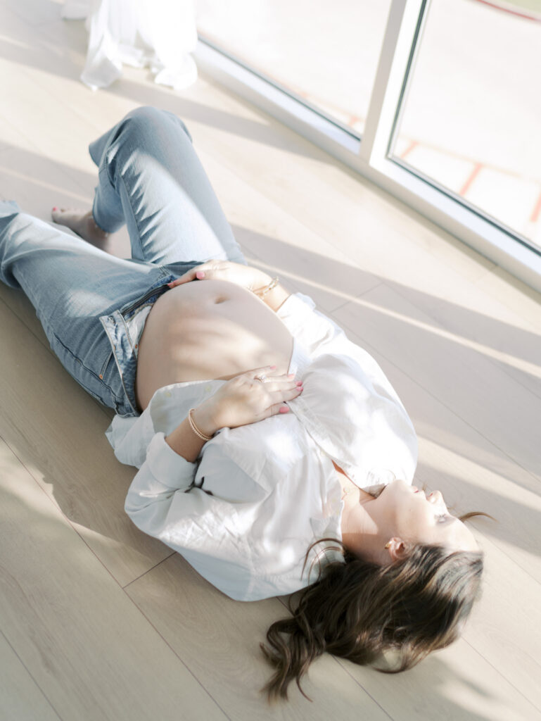 studio maternity photos in colorado springs on mom on floor with window light hitting belly