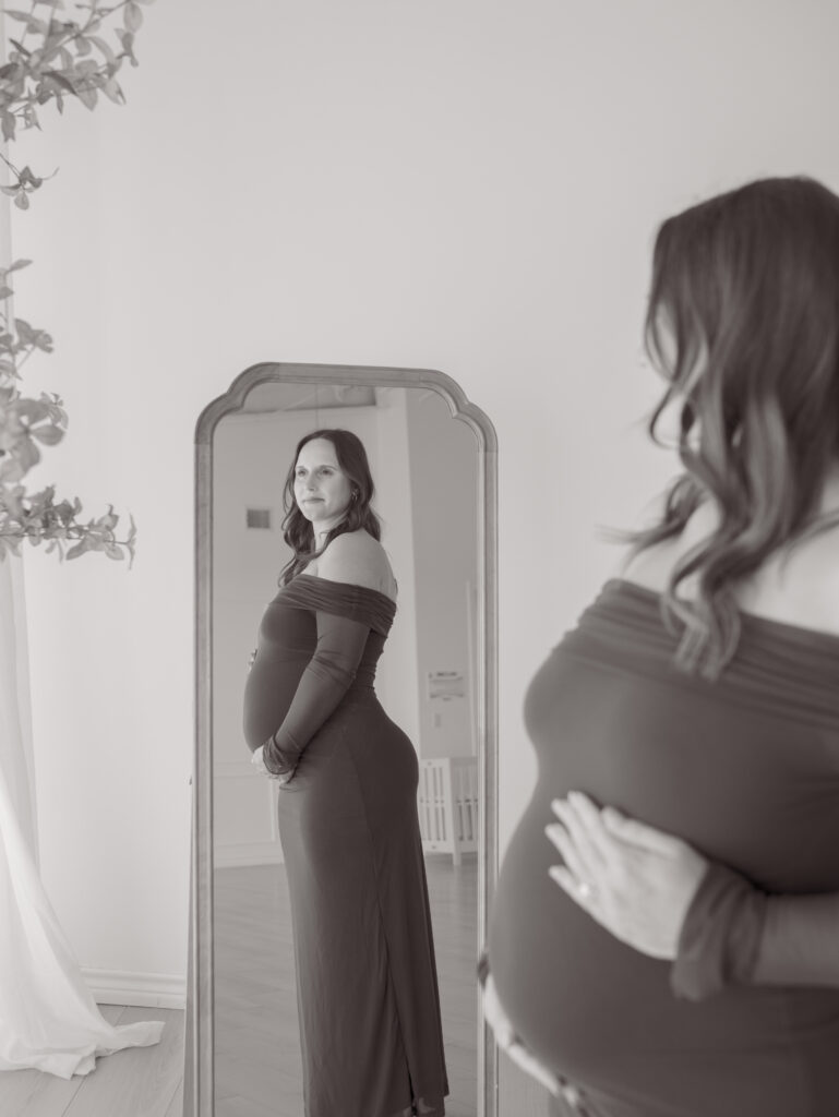 expecting mom looking in a mirror at growing belly