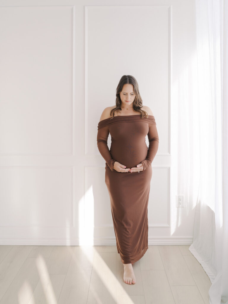 expecting mom in long tight dress holding bottom of belly for Maternity Photos in Colorado Springs
