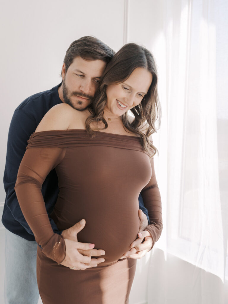 husband hugging wifes pregnant belly from behind