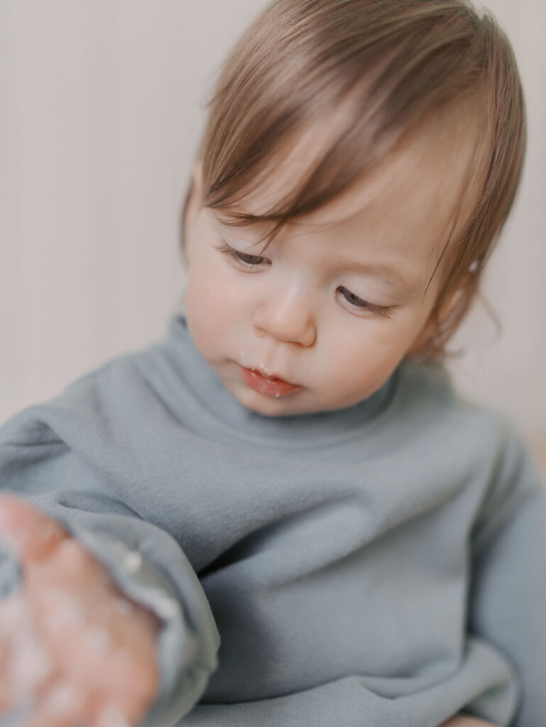 one year looking at cake on his hand