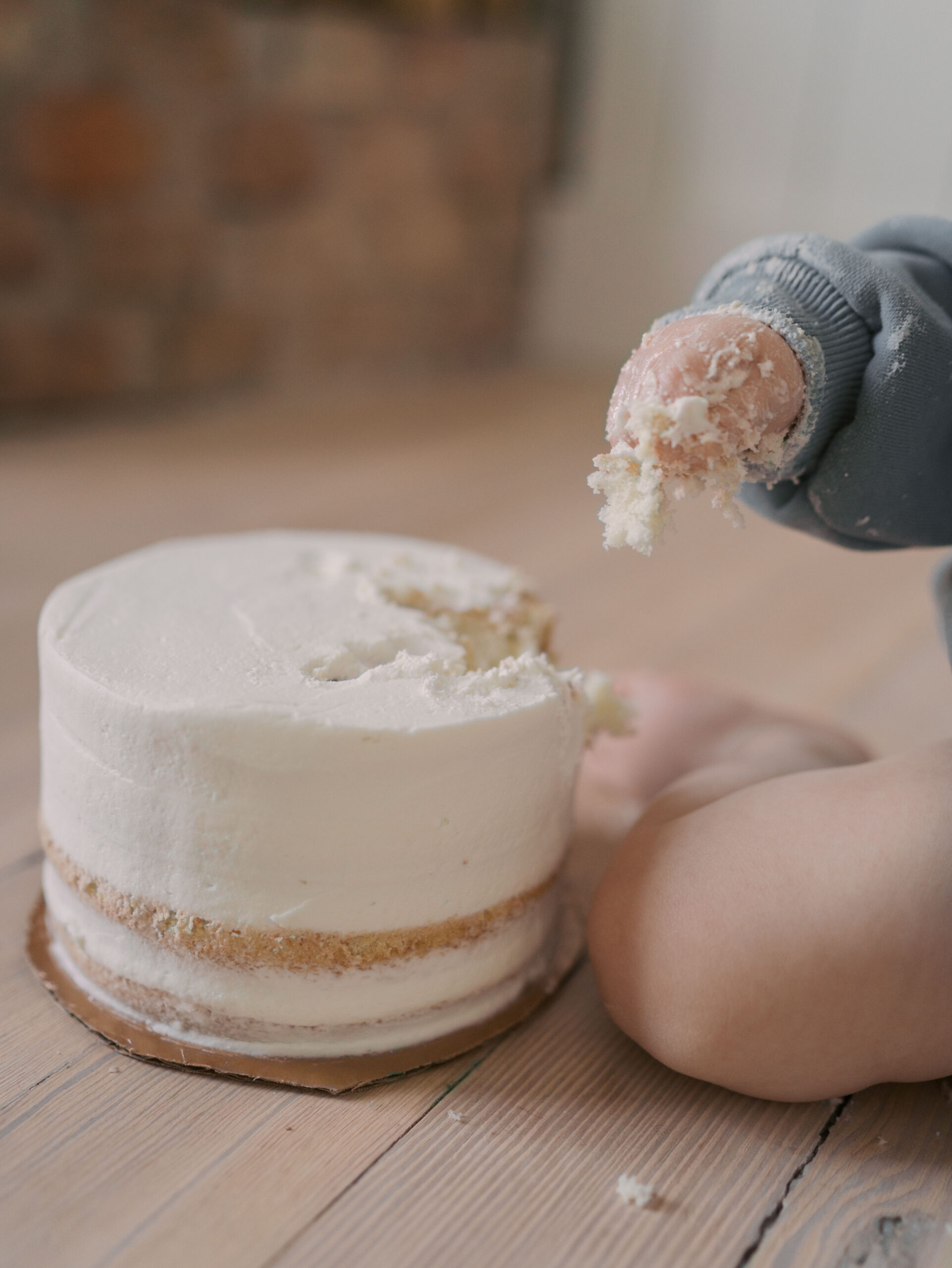 one year olds smash cake with hand above full of cake crumbs