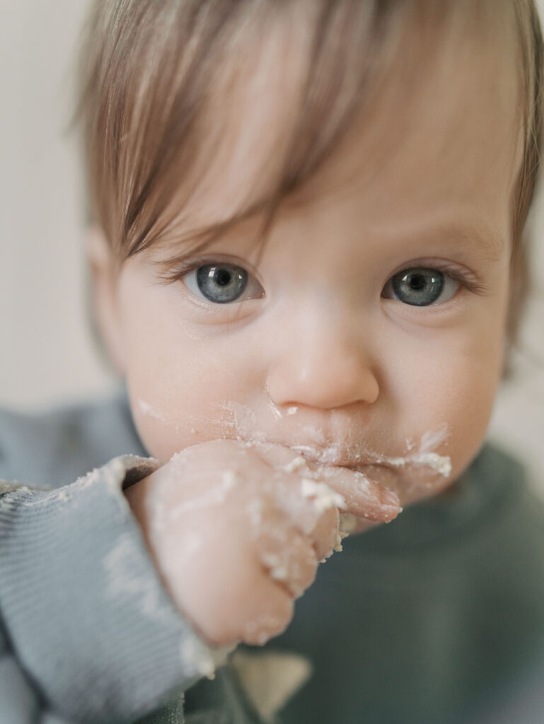 one year milestone photo close up of one year old eating cake