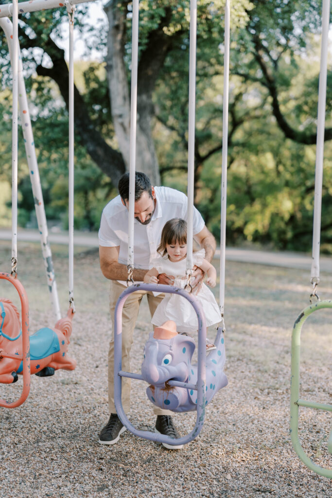 dad helping daughter onto swing