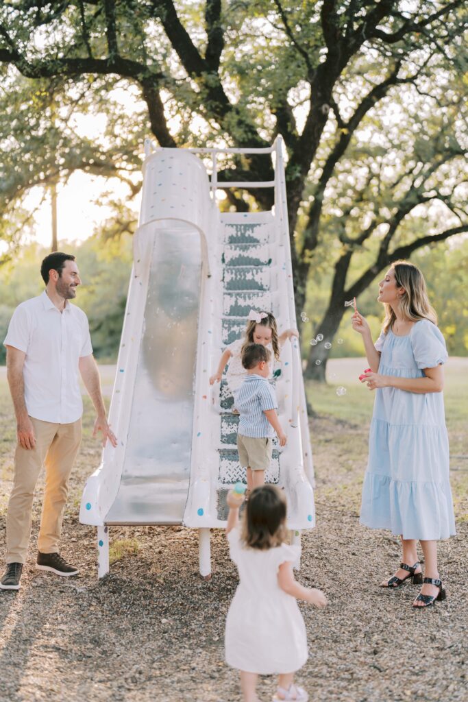 mom blowing bubbles with family at a park taken by Story-Driven Family Photography in Colorado Springs