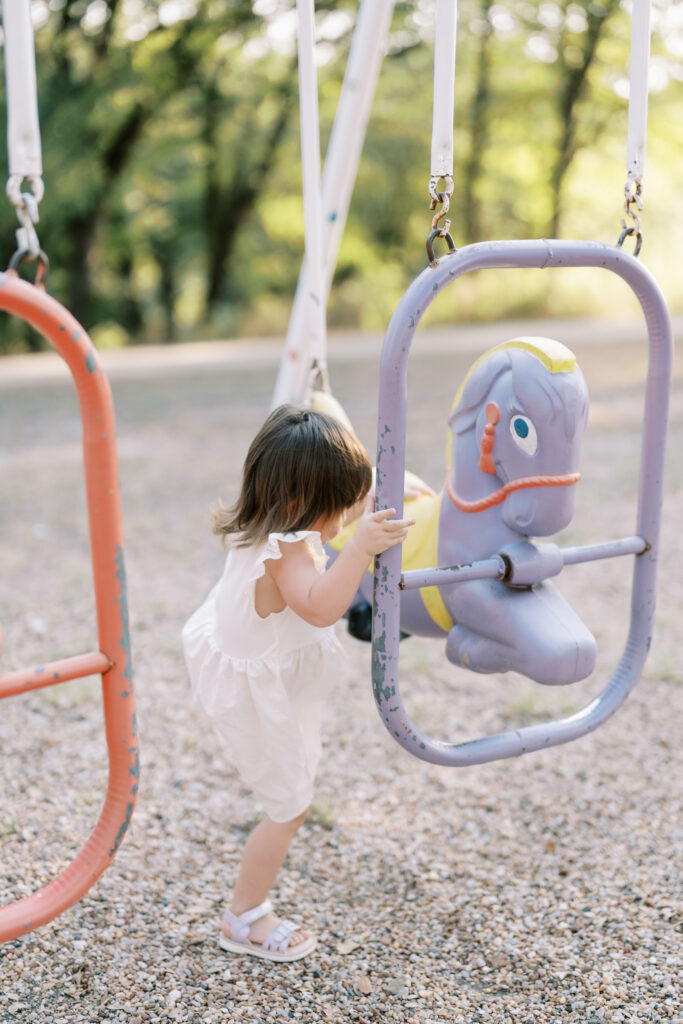 little girl getting on horse swing