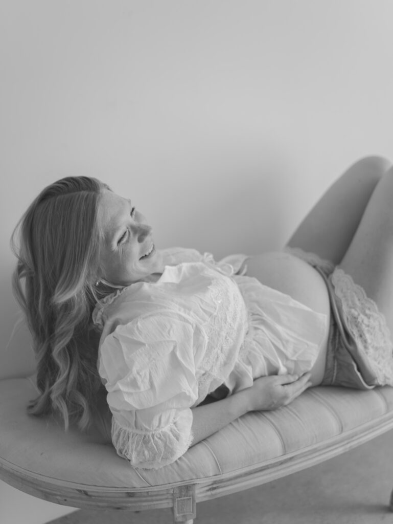 expecting mom laughing while laying on elbows in colorado springs photo studio