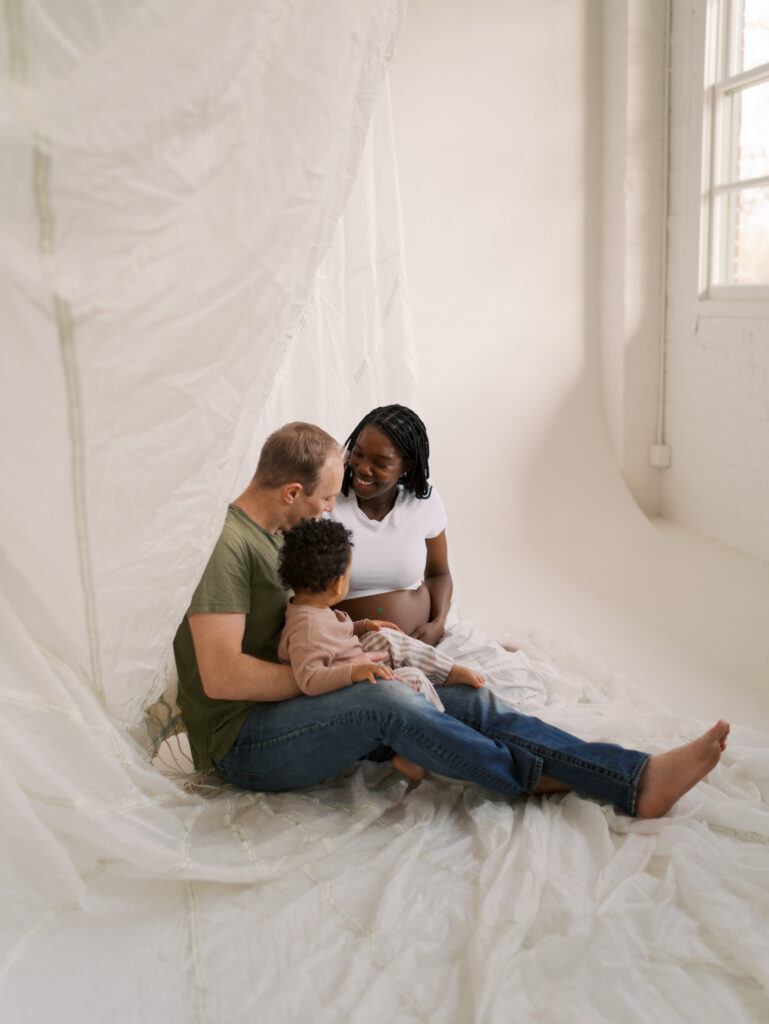 family of three sitting and snuggling for Studio Maternity Photos Denver by Lauren Bounds Photography