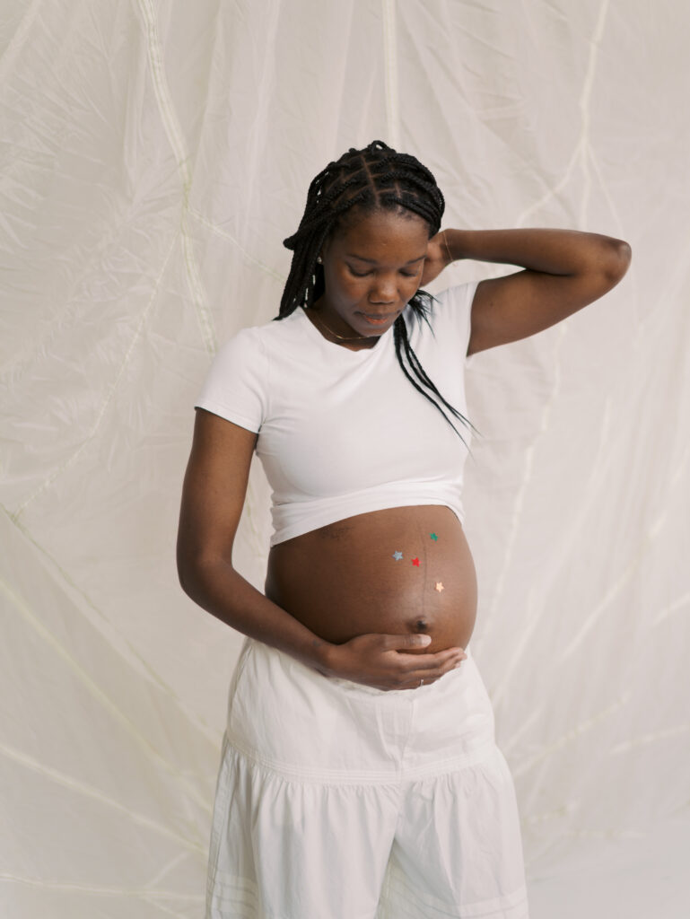 mom gazing at expecting stomach in studio in denver for maternity photos
