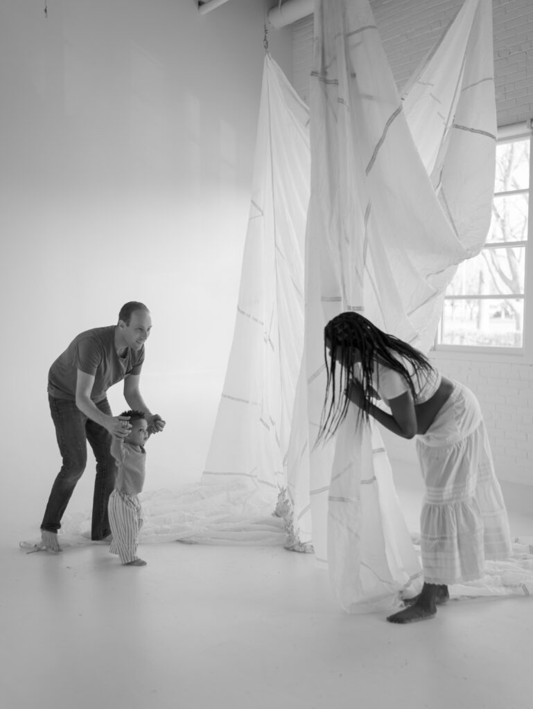 family playing- mom hides behind curtain from little boy and man for Studio Maternity Photos Denver by Lauren Bounds Photography