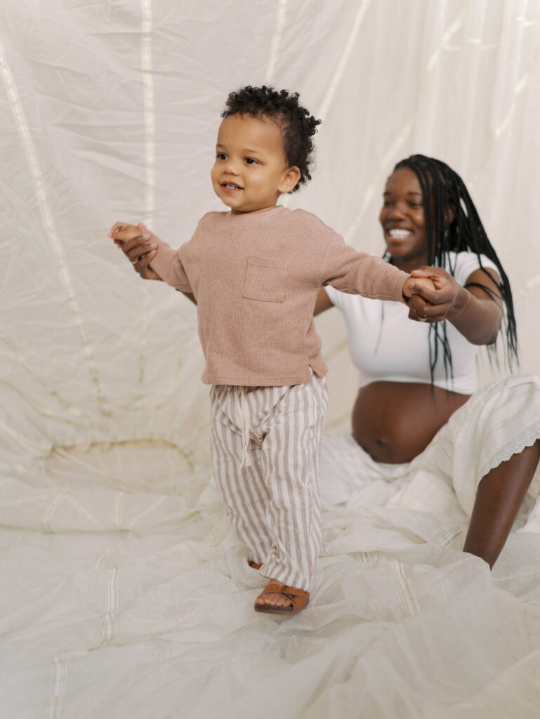 little boy running and laughing as mom smiles on holding his hand