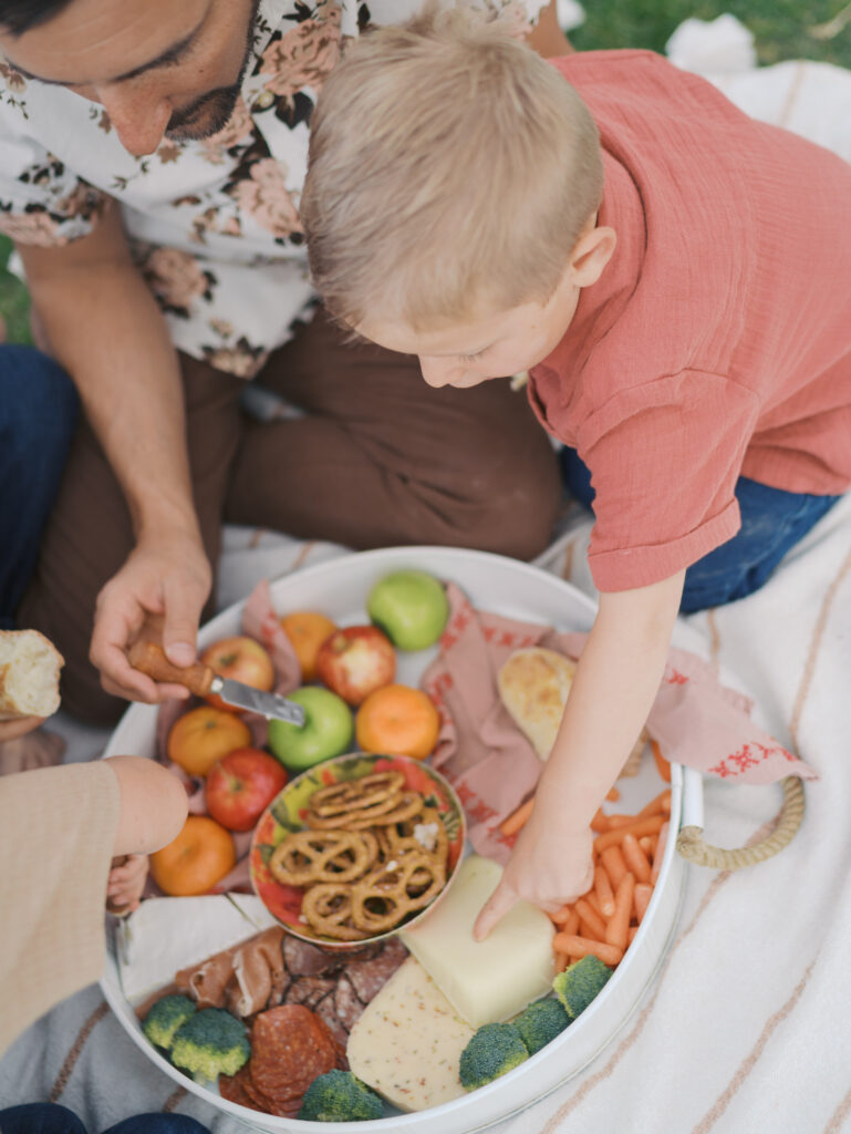 kid and family getting food from charcuterie platter during a family picnic in Colorado Springs, CO