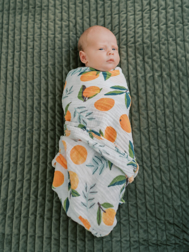 newborn baby swaddled in orange print swaddle