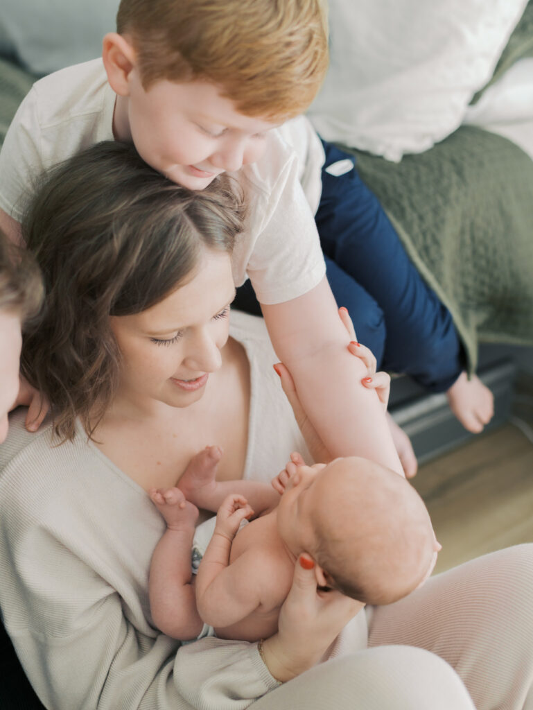 big brother and mom look at newborn baby for Colorado Springs Newborn Photography