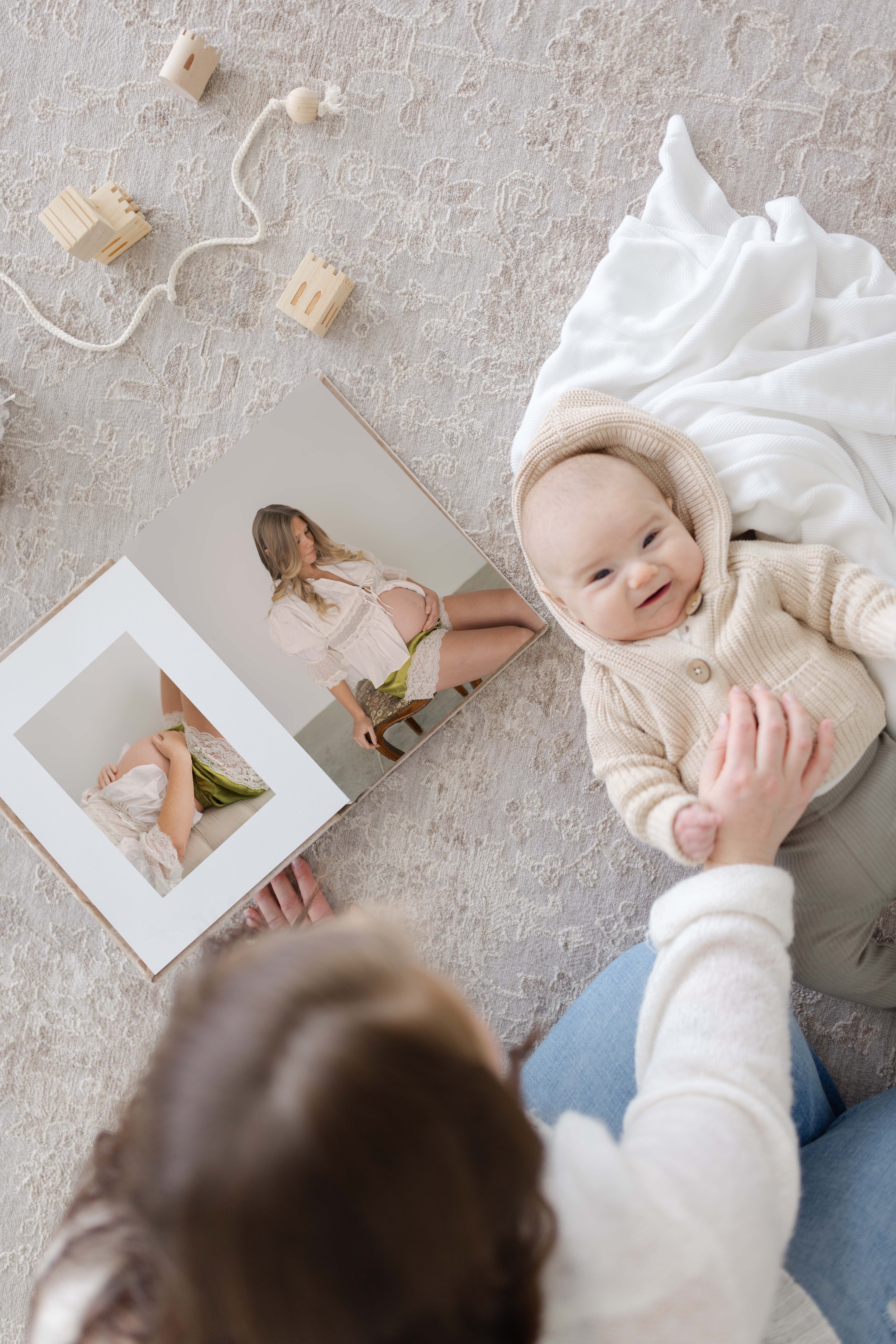 mom and baby with album showing artwork from Lauren bounds photography in colorado springs