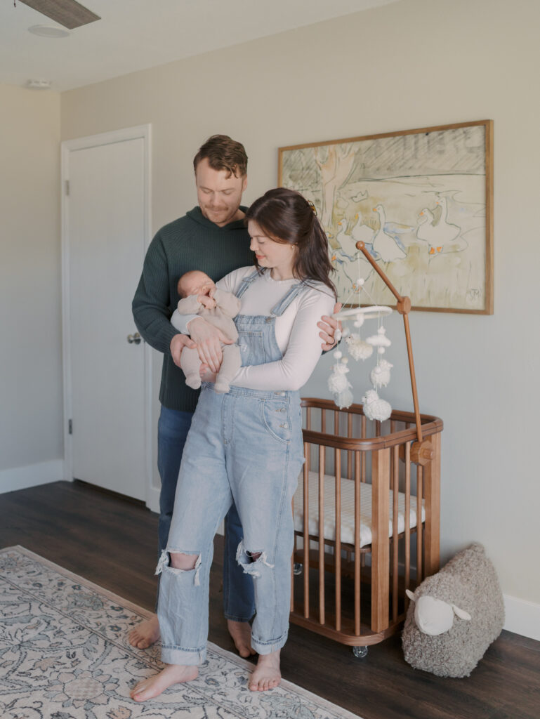 couple standing in front of crib with newborn baby in arms for Colorado Springs, CO newborn photos