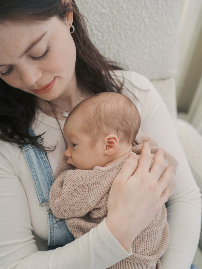 mom holding newborn baby close to chest as she gazes down at him for What to expect during a newborn session by Lauren Bounds Photography