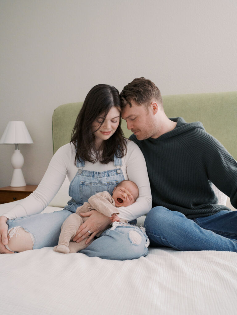 Couple on bed with newborn baby for blog post What to expect during a newborn session by Lauren Bounds Photography